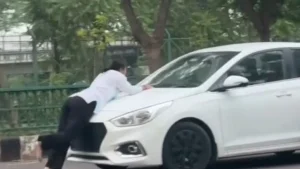Barefeet, she is pedalling backwards, with her body bent at the middle, covering the car's